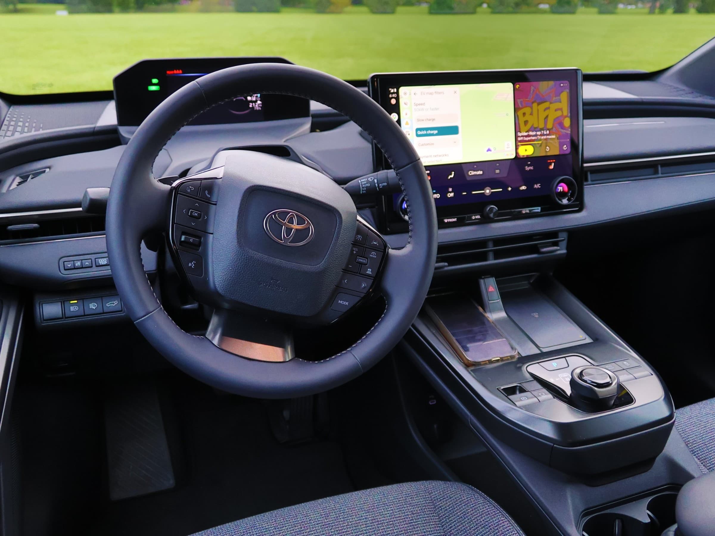 Toyota bZ dashboard seen from the driver’s seat, with a compact gauge display above the steering wheel, a large center touchscreen and a rotary gear selector.