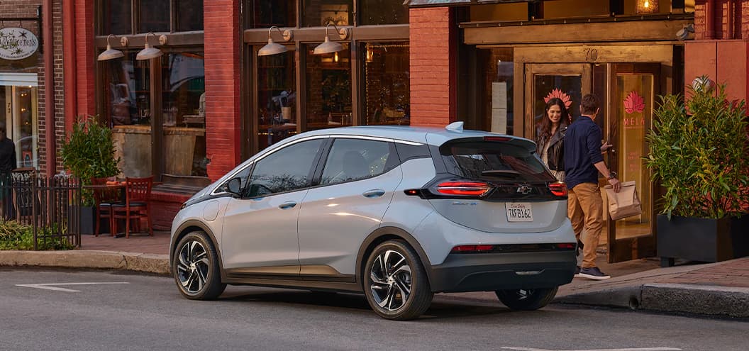 Chevy Bolt parked outside restaurant next to couple