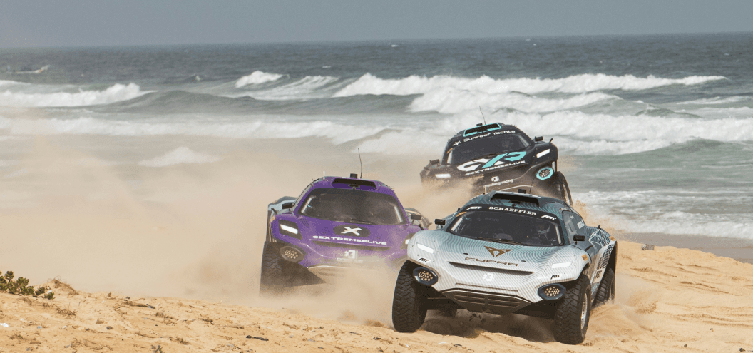 extreme e vehicles racing along beach