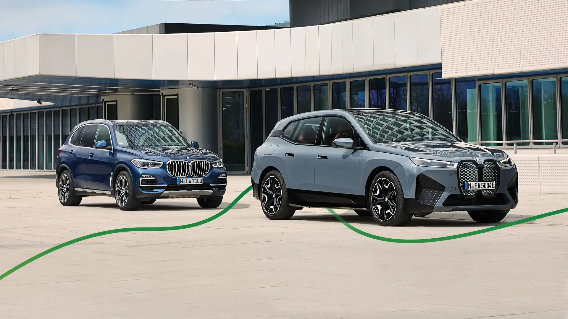Picture of a BMW iX X50 and a BMW X5 M50i parked next to a building