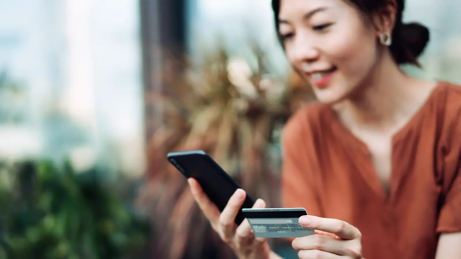 woman looking at her phone and credit card
