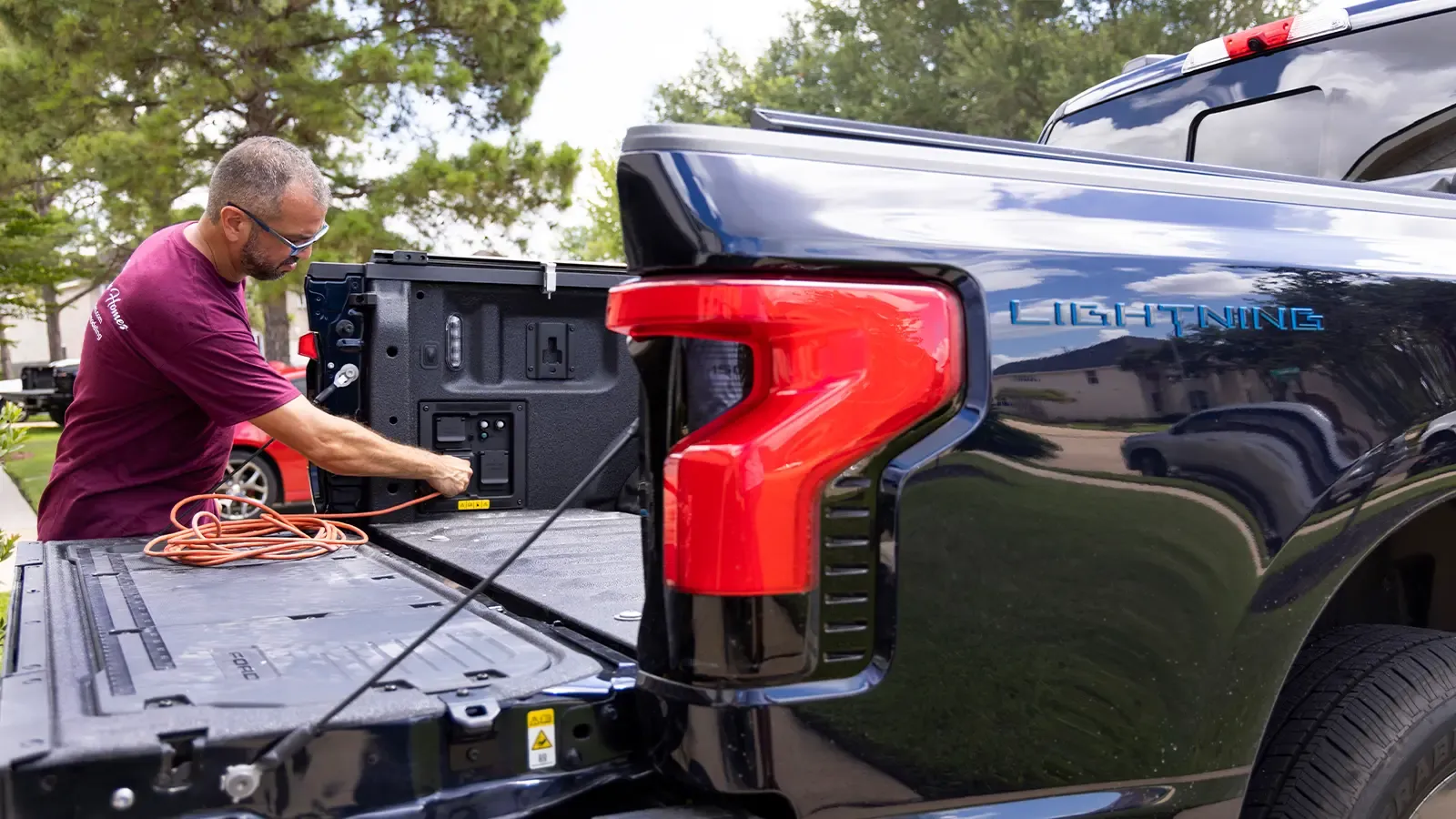 Man plugging power cord into ford lightning truck