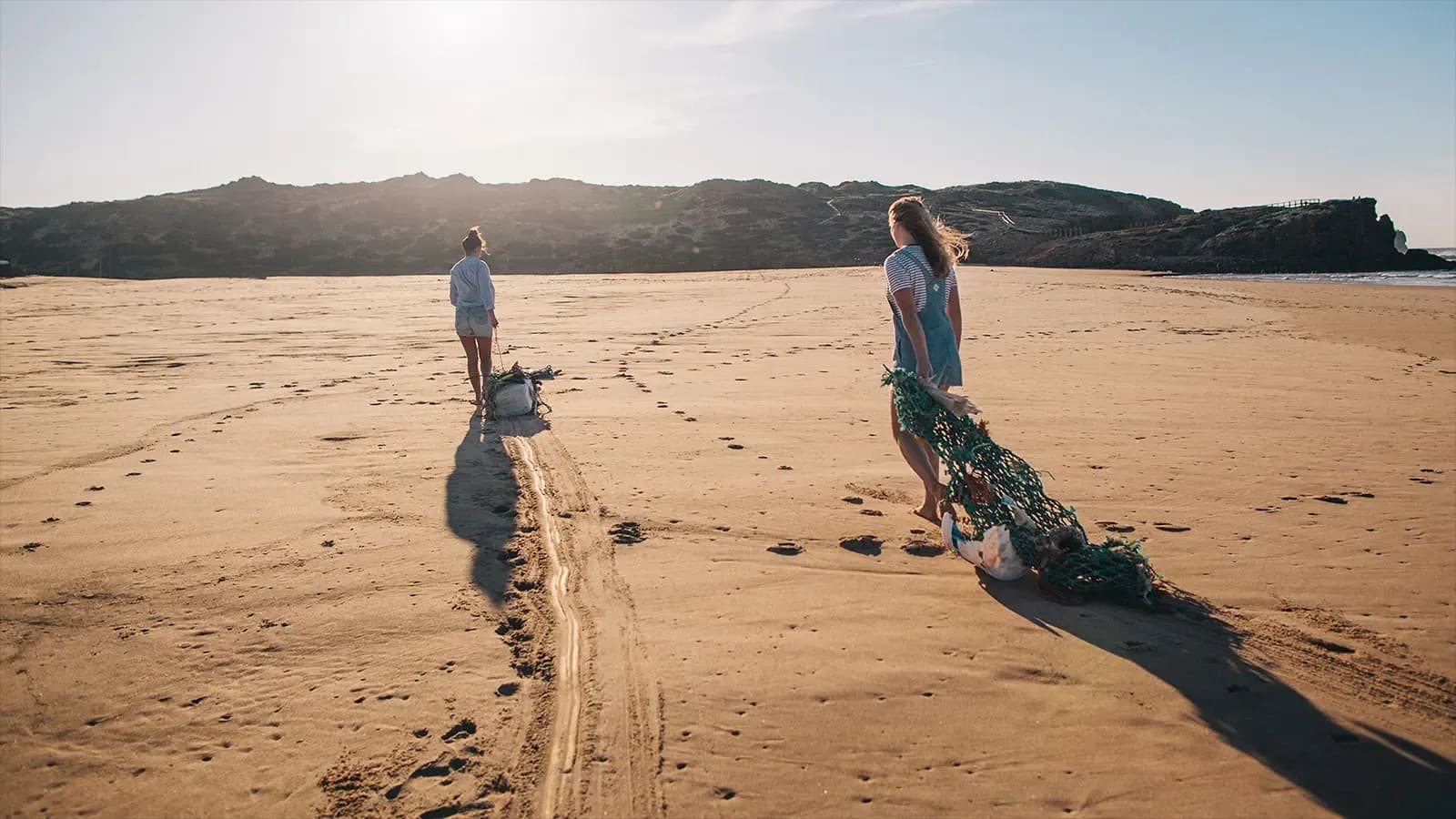 two people cleaning up the beach
