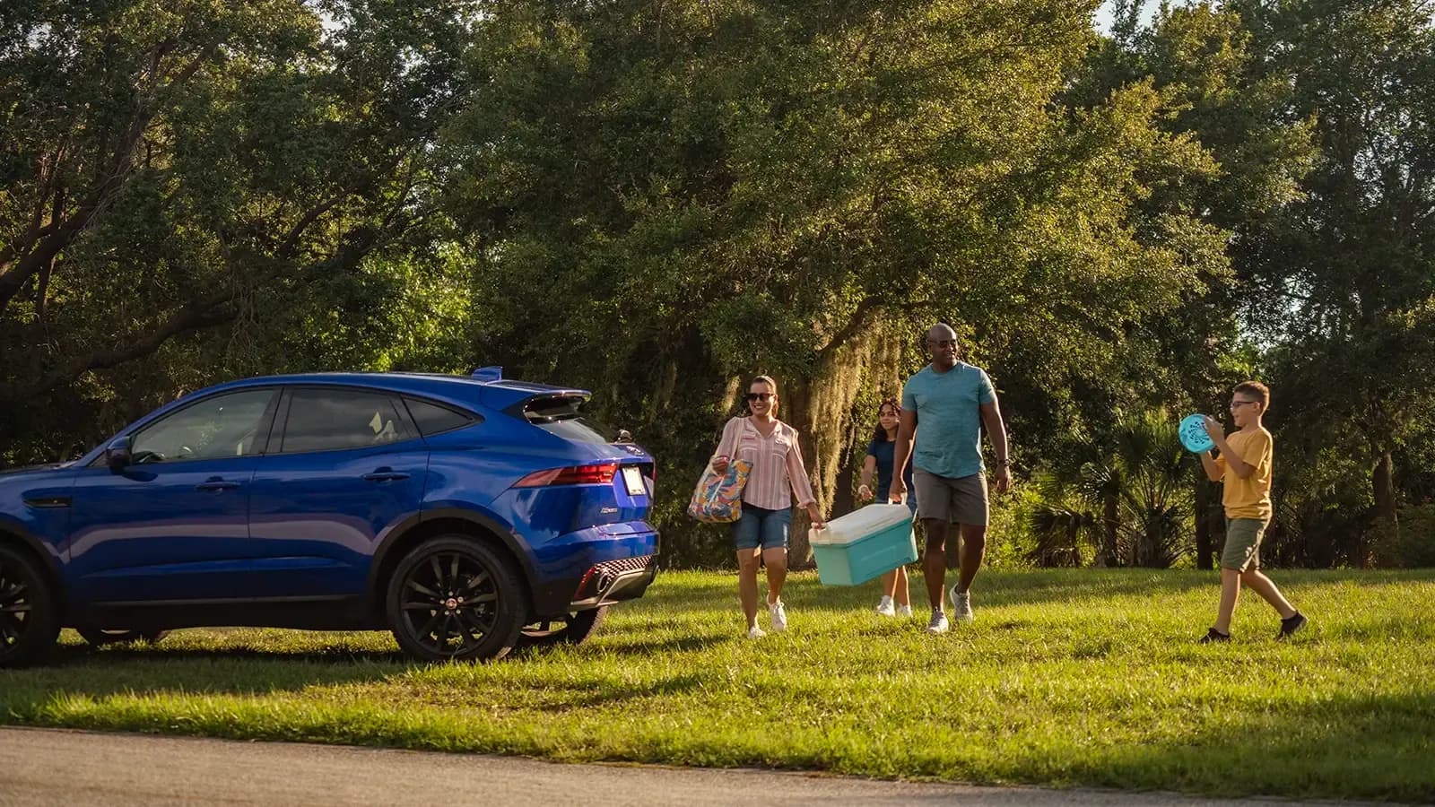 man and pet dog walking by a hybrid car