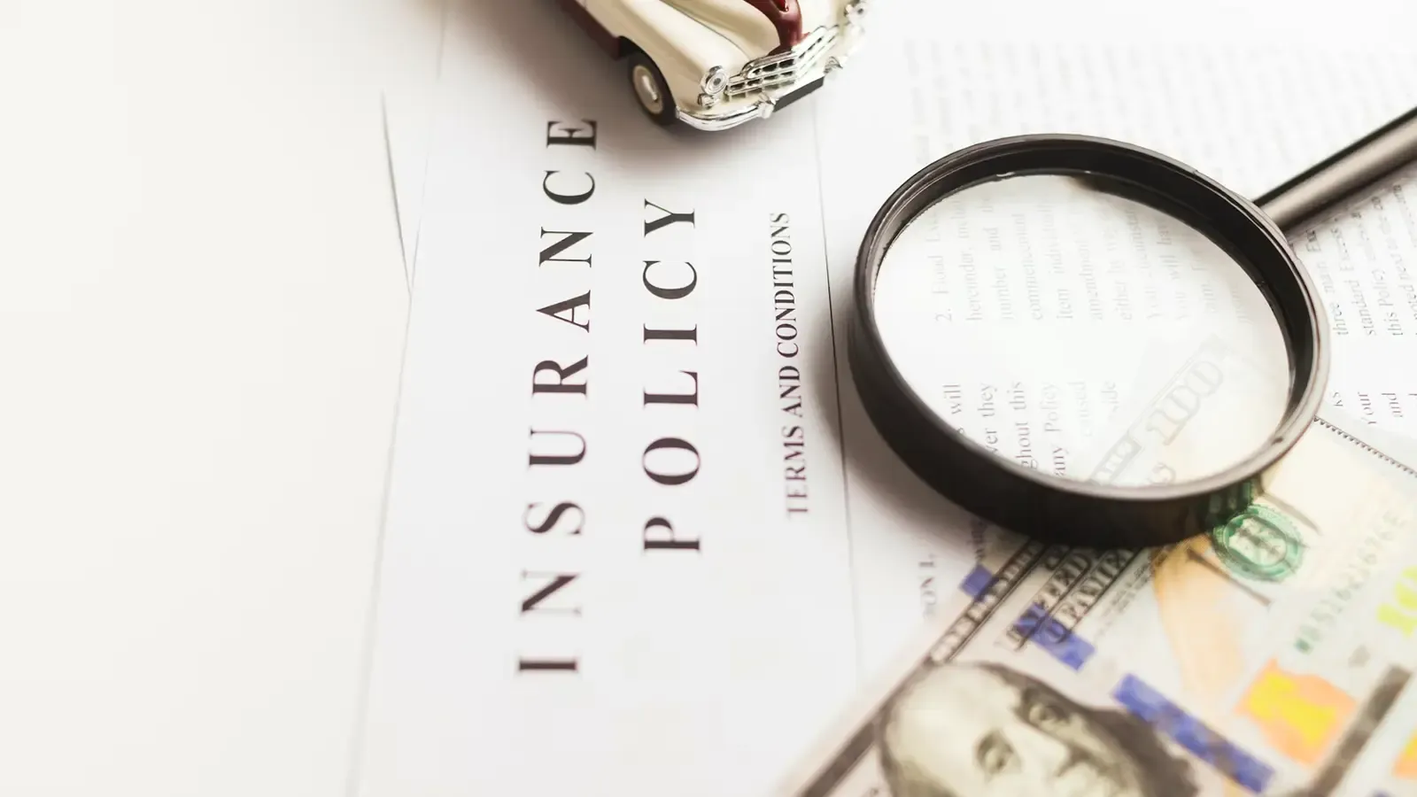 Insurance Notes terms and conditions with a car toy and 100 dollar bill