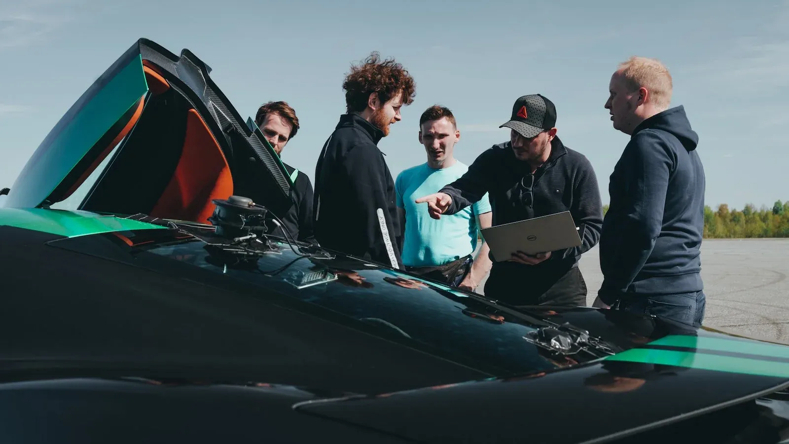 Group of men surrounding electric race car 