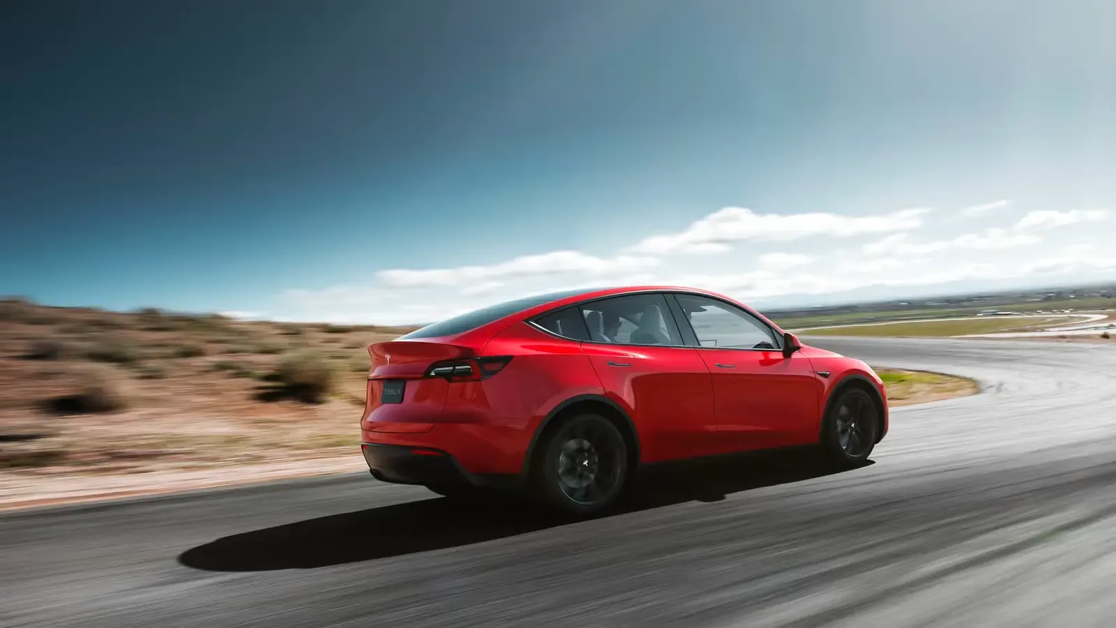 Red Tesla Model Y side view on the road 