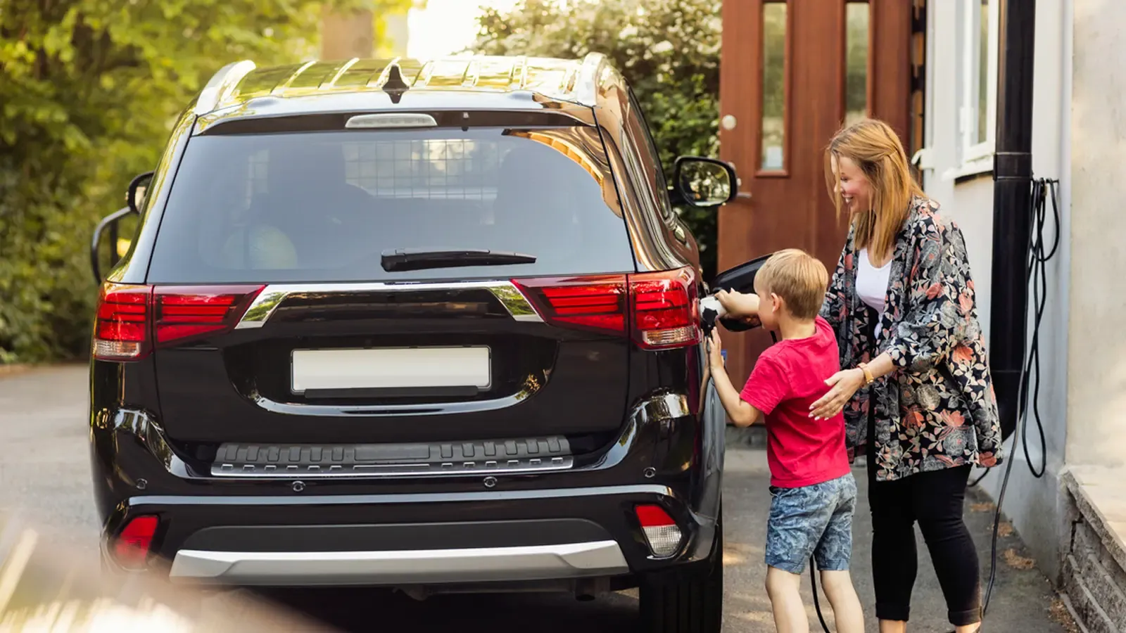 Mom and son charging car at home 
