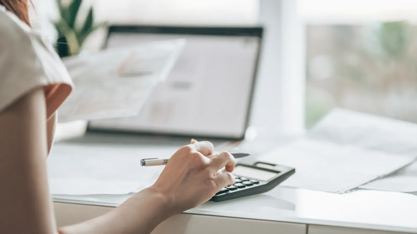 woman doing her taxes using a calculator 