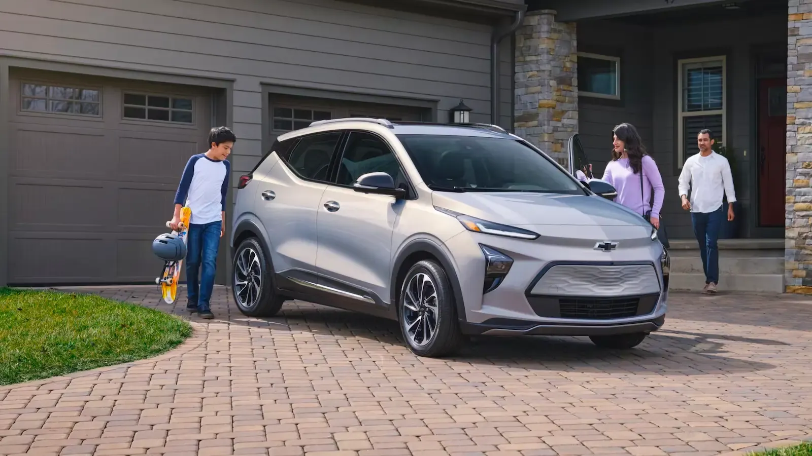 Chevrolet Bolt EUV parked in a driveway with a family nearby