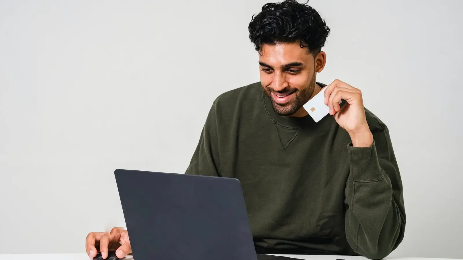Man smiling and looking at his laptop with his credit card
