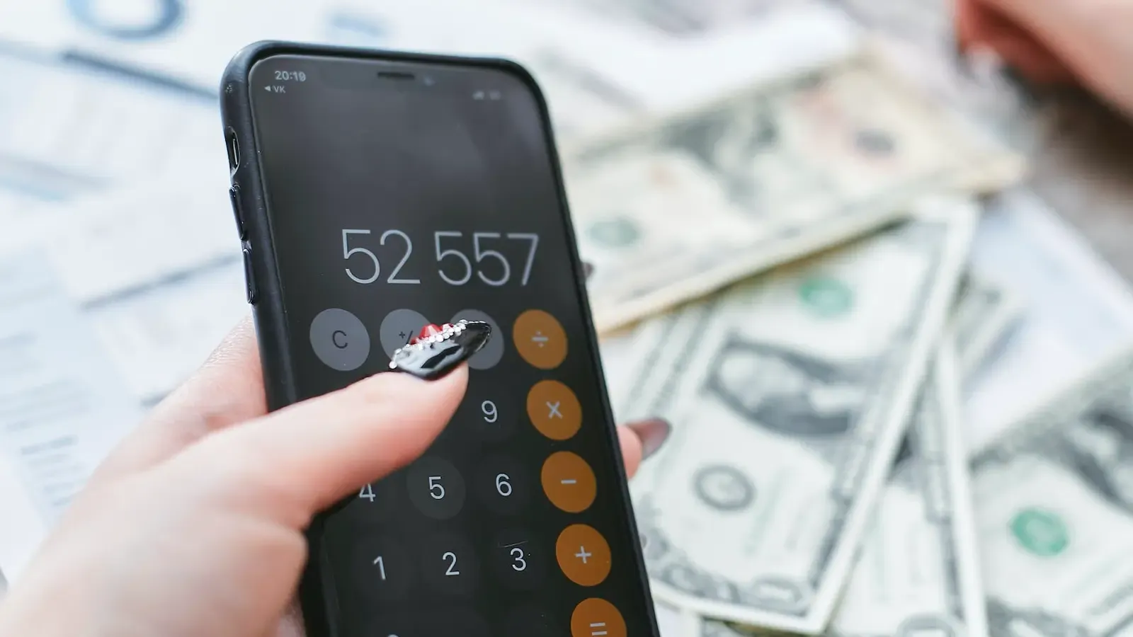 Person holding calculator and money in the background