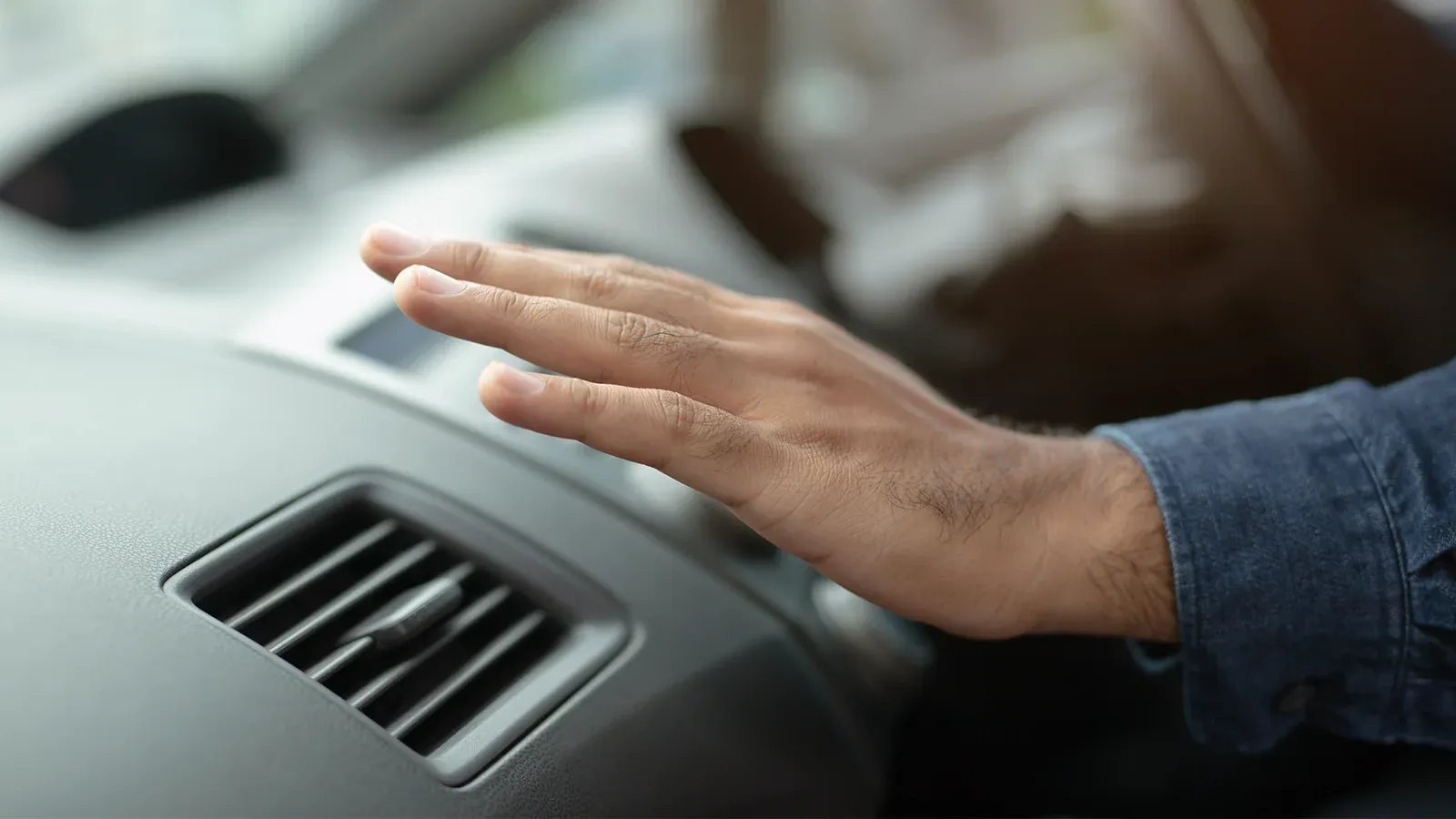 Driver feeling the airflow from the electric car's air conditioning vent