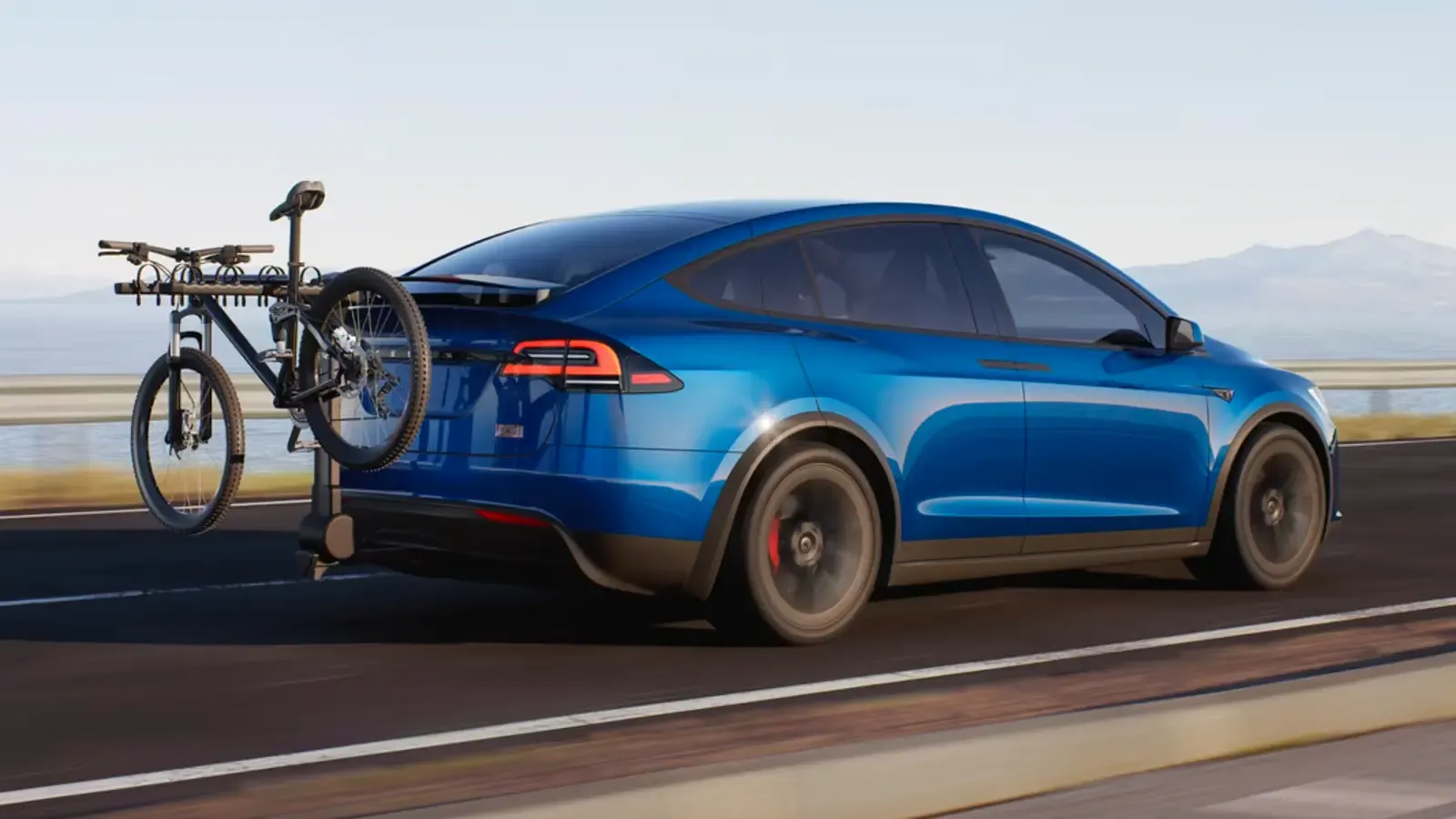Blue Tesla Model X with a bike attached to the back of the car