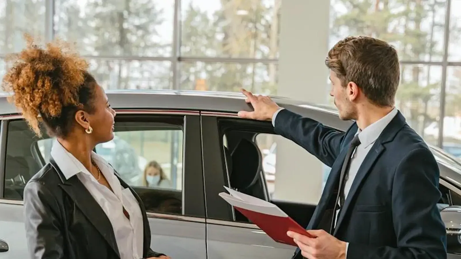 two people in a car dealership looking at a car 