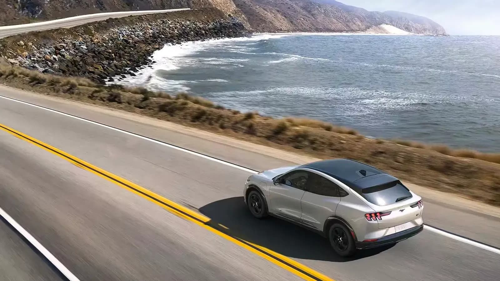 Ford Mustang Mach E driving on a highway by the sea