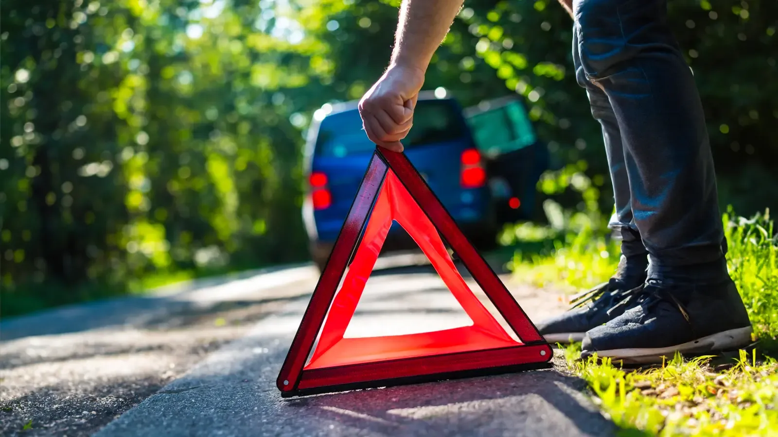 Man putting down a warning sign by a car