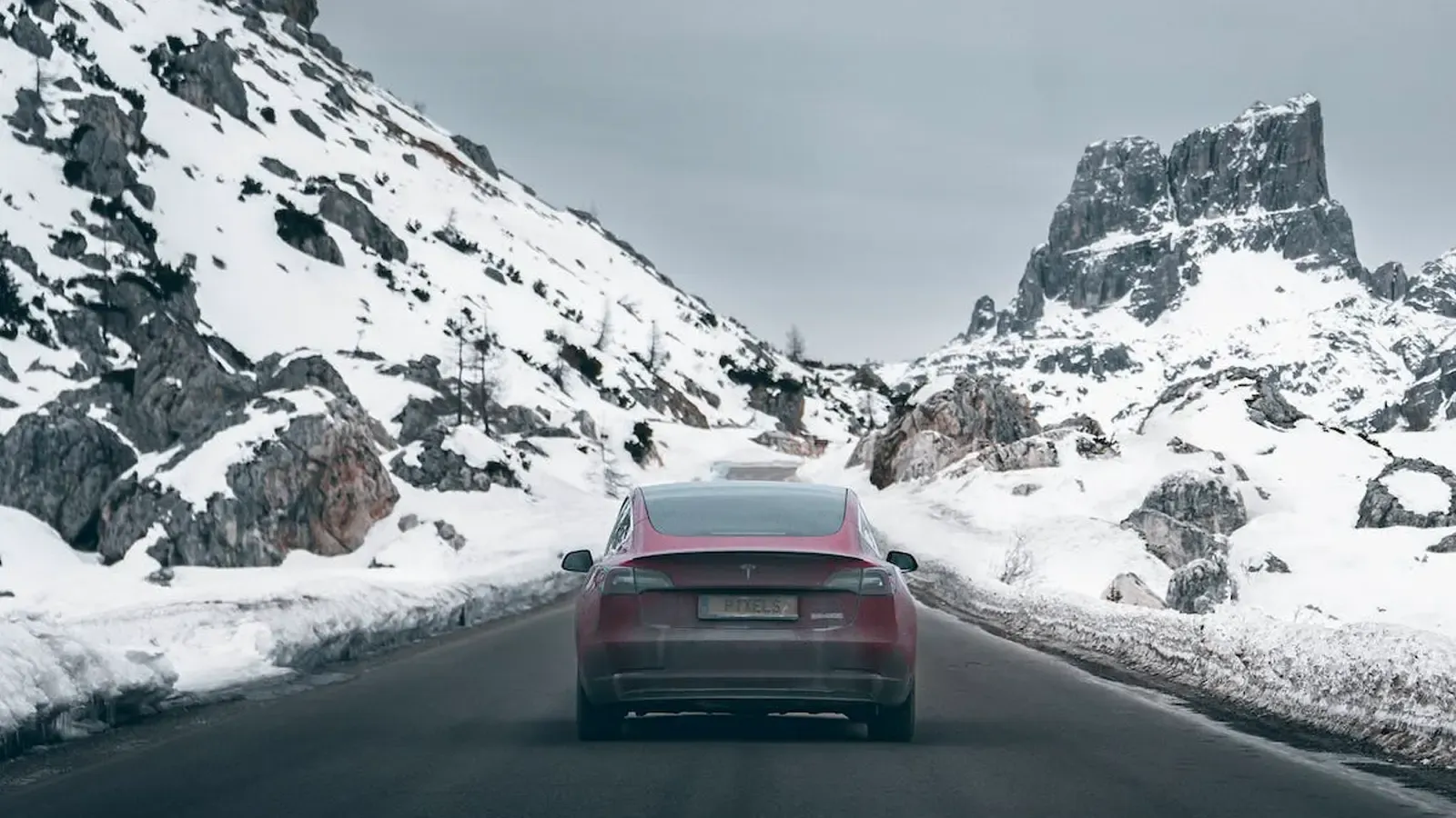 A frosted Tesla driving on a wintery road