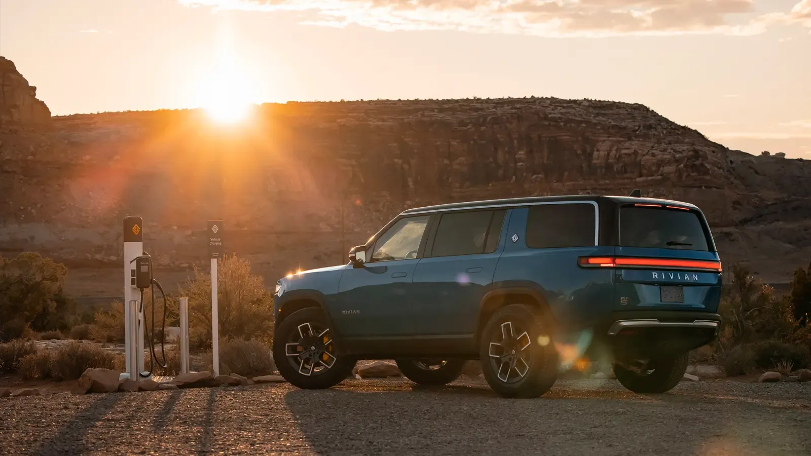 Rivian Pickup being charged outside in a mountainous scene. 