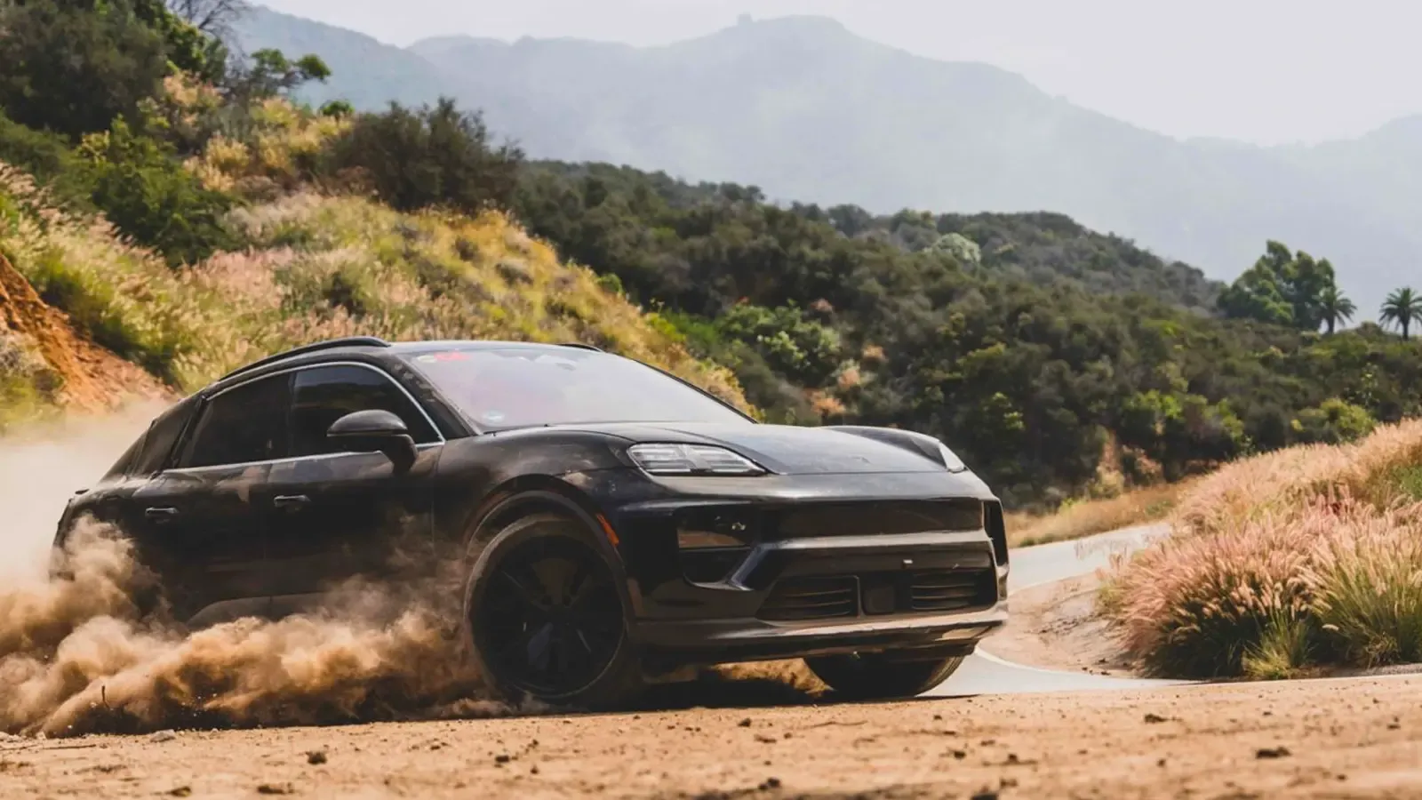 Porsche Macan EV front exterior view driving on a dirt path