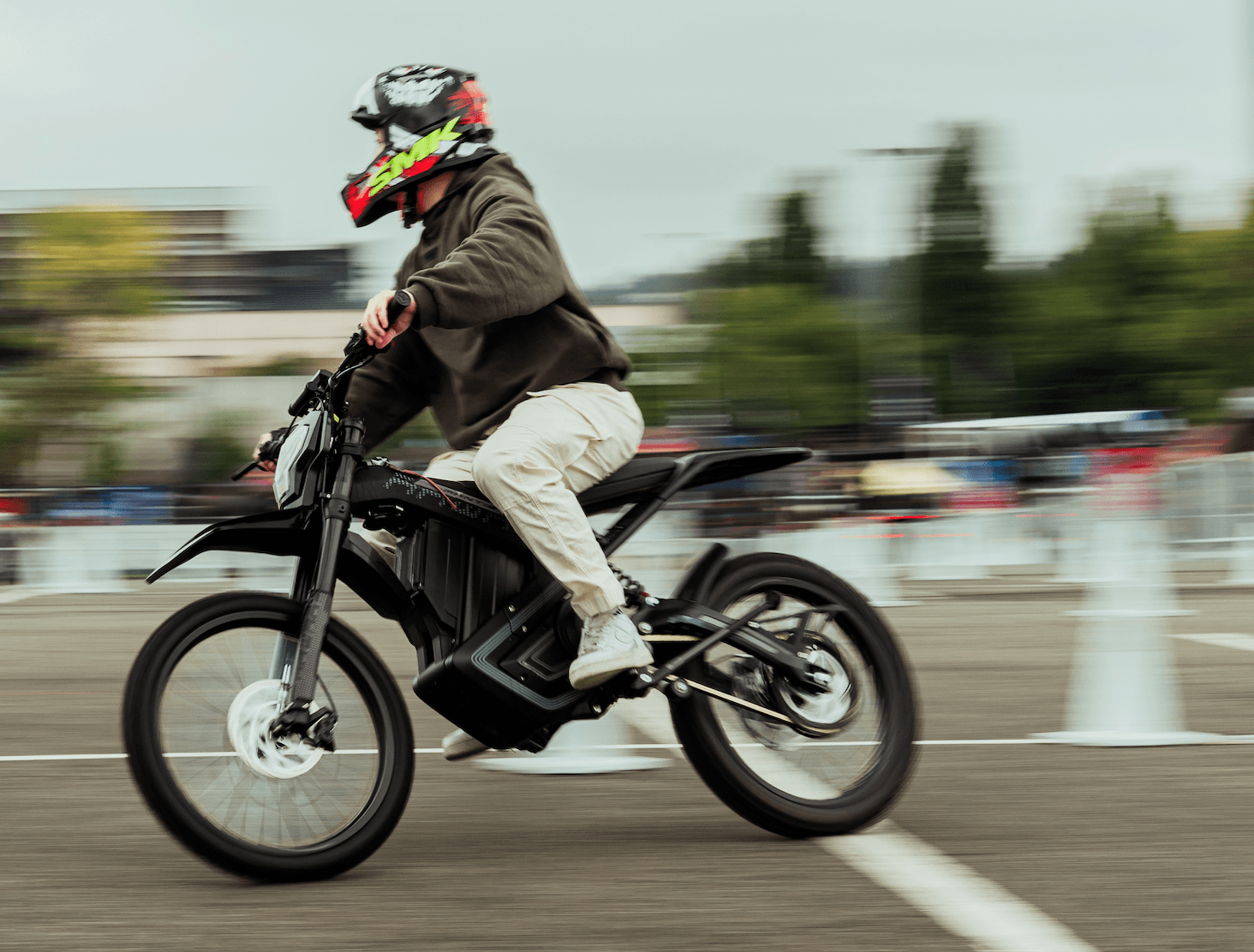A rider on a black electric dirt bike leans into a turn on a course.