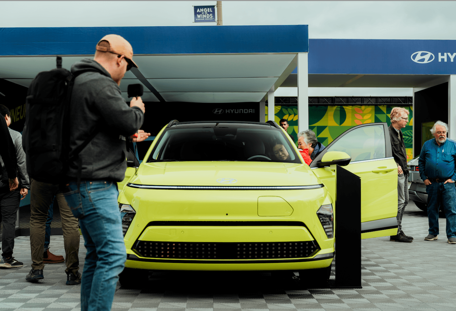 Front view of a lime green electric SUV with people gathered around it at an expo booth.