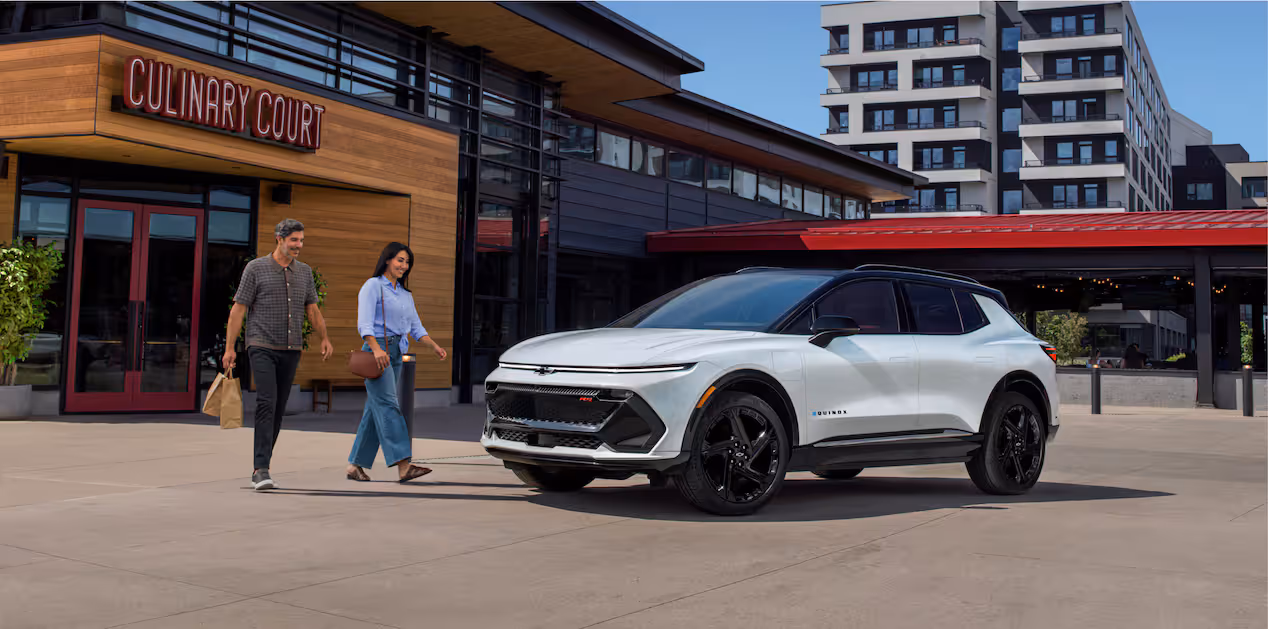 people walking towards a white Chevy Equinox EV 