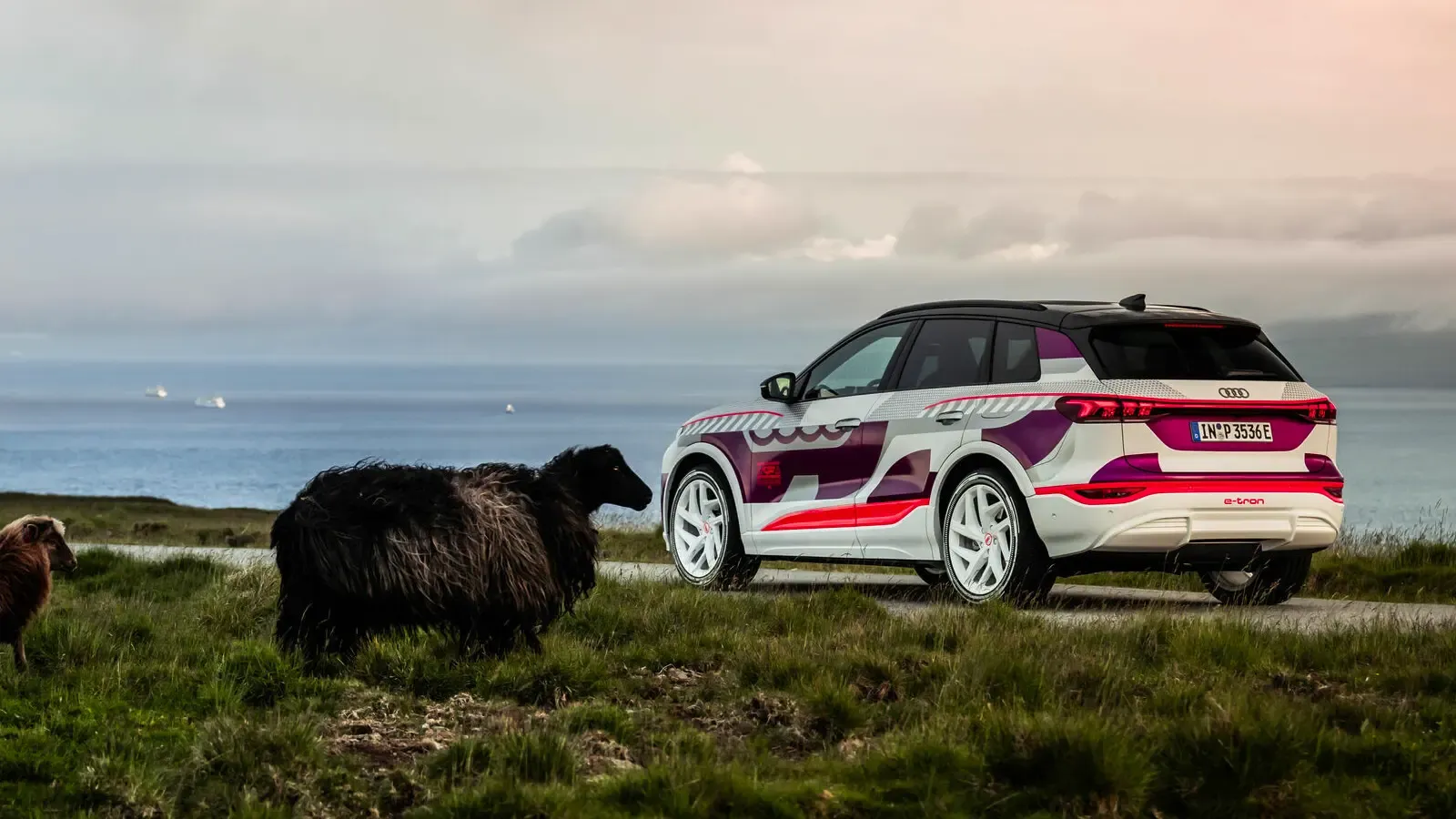 Audi Q6 e-tron prototype parked by the sea and a sheep by the side.