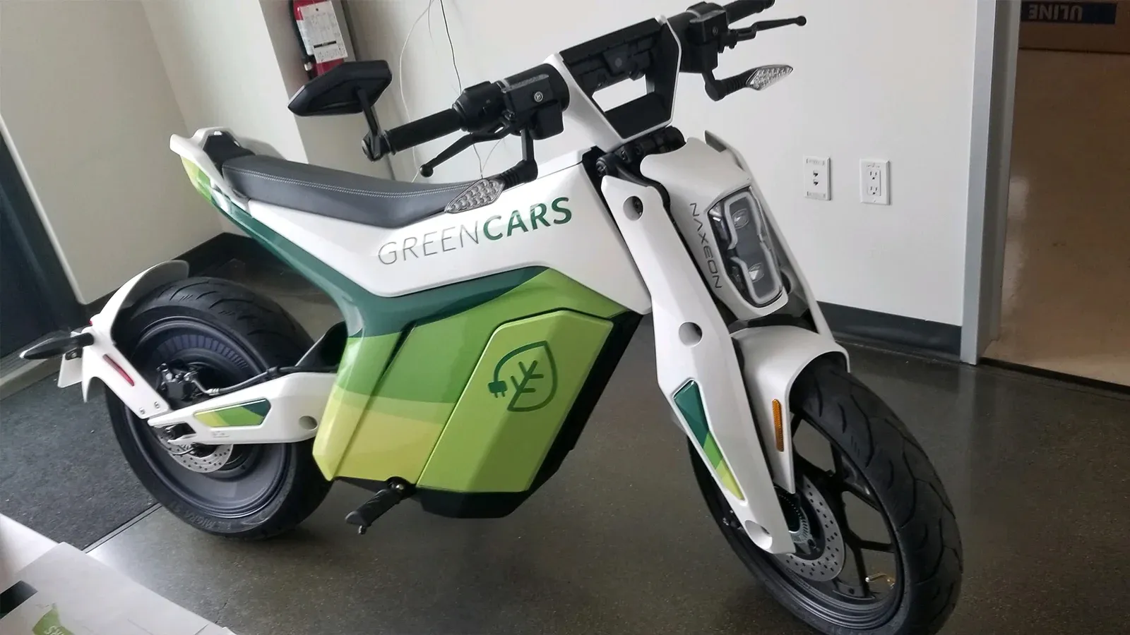 Vista delantera de tres cuartos de una e-bike Naxeon I AM con paneles blancos y verdes.