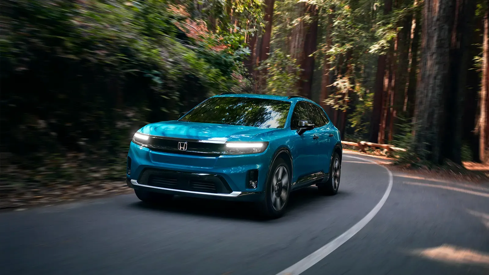 A teal Honda prologue driving through the forest.