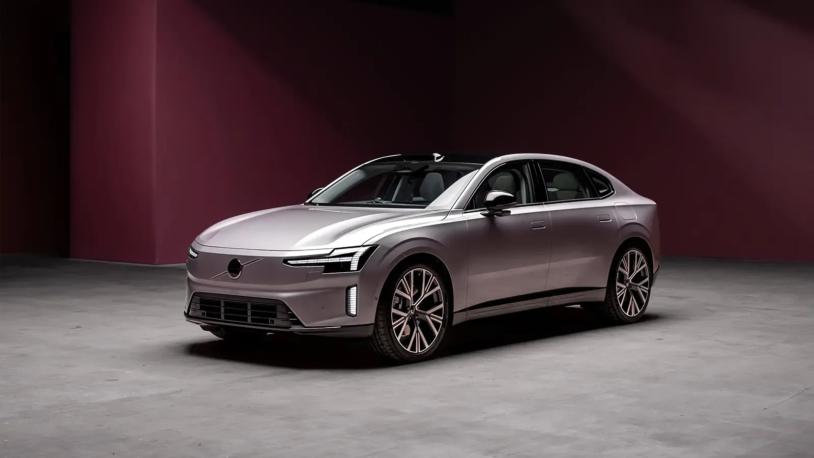 Silver Volvo ES90 against a red backdrop.