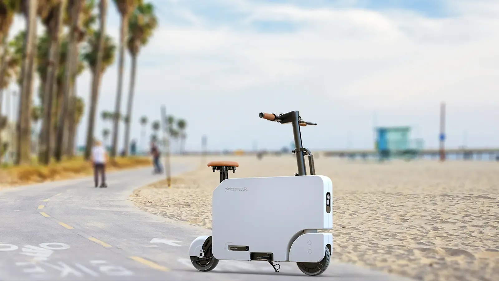 A Honda Motocompacto on the walkway near a beach