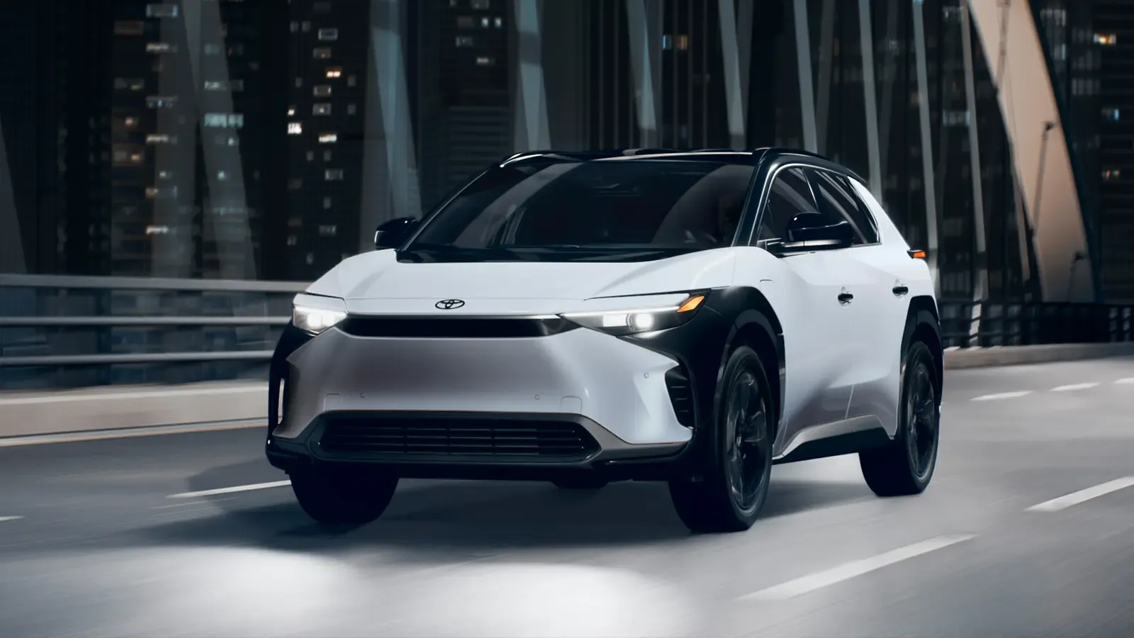A white 2025 Toyota bZ4X driving across a bridge