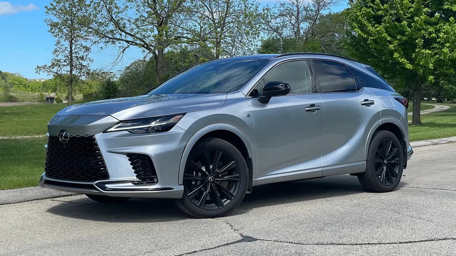 A silver 2025 Lexus RX 500h F Sport in a park