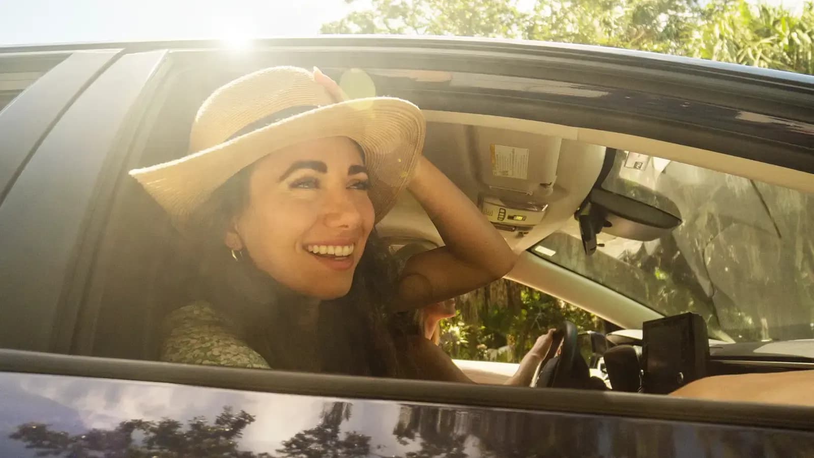 smiling woman riding in a greencar with the windows down and wind blowing
