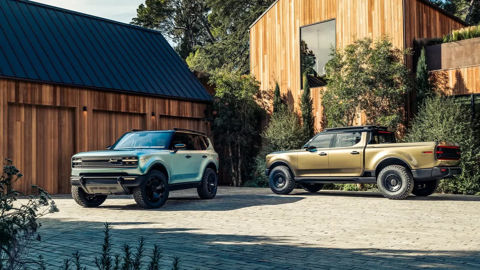 The Scout Terra and the Traveler parked in front of a modern barn at the golden hour