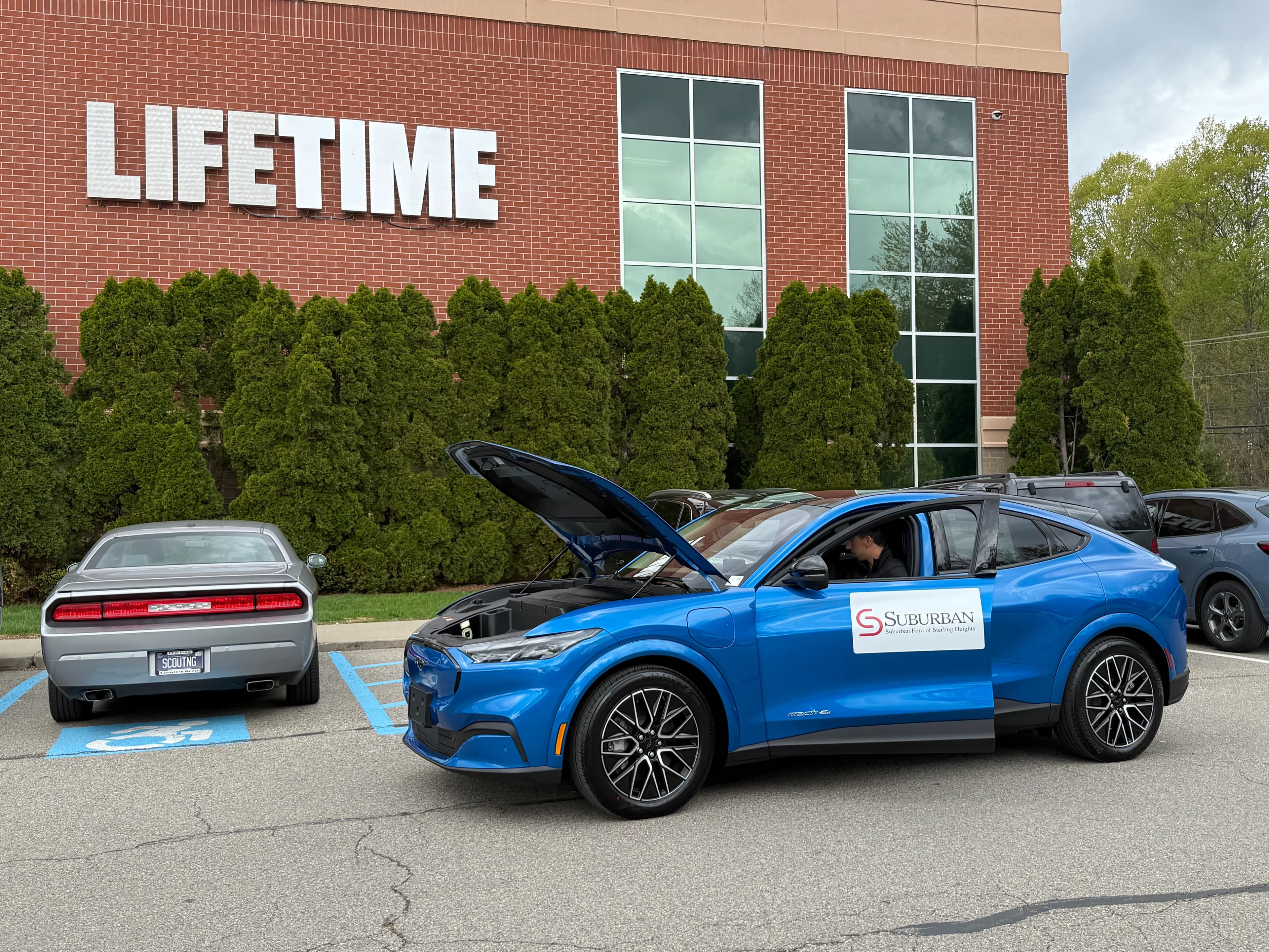 Un Ford Mustang Mach-E azul con el cofre delantero abierto en el estacionamiento de Lifetime.