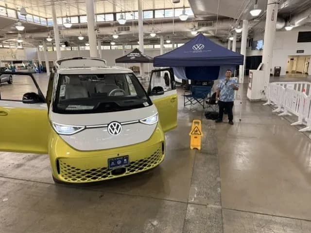 Vista frontal de una Volkswagen ID. Buzz con ambas puertas delanteras abiertas en un puesto interior del evento.
