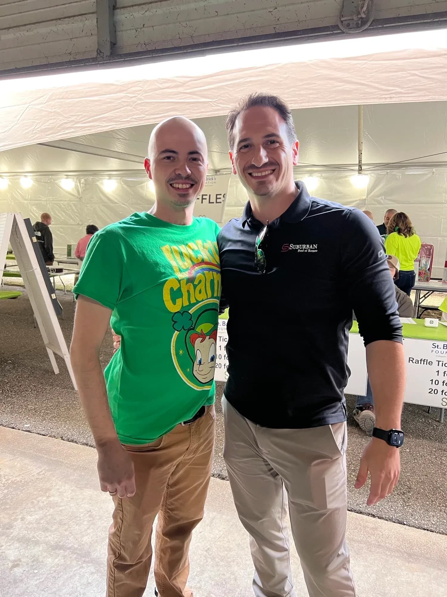Two people stand together under a tent at a fundraiser event.