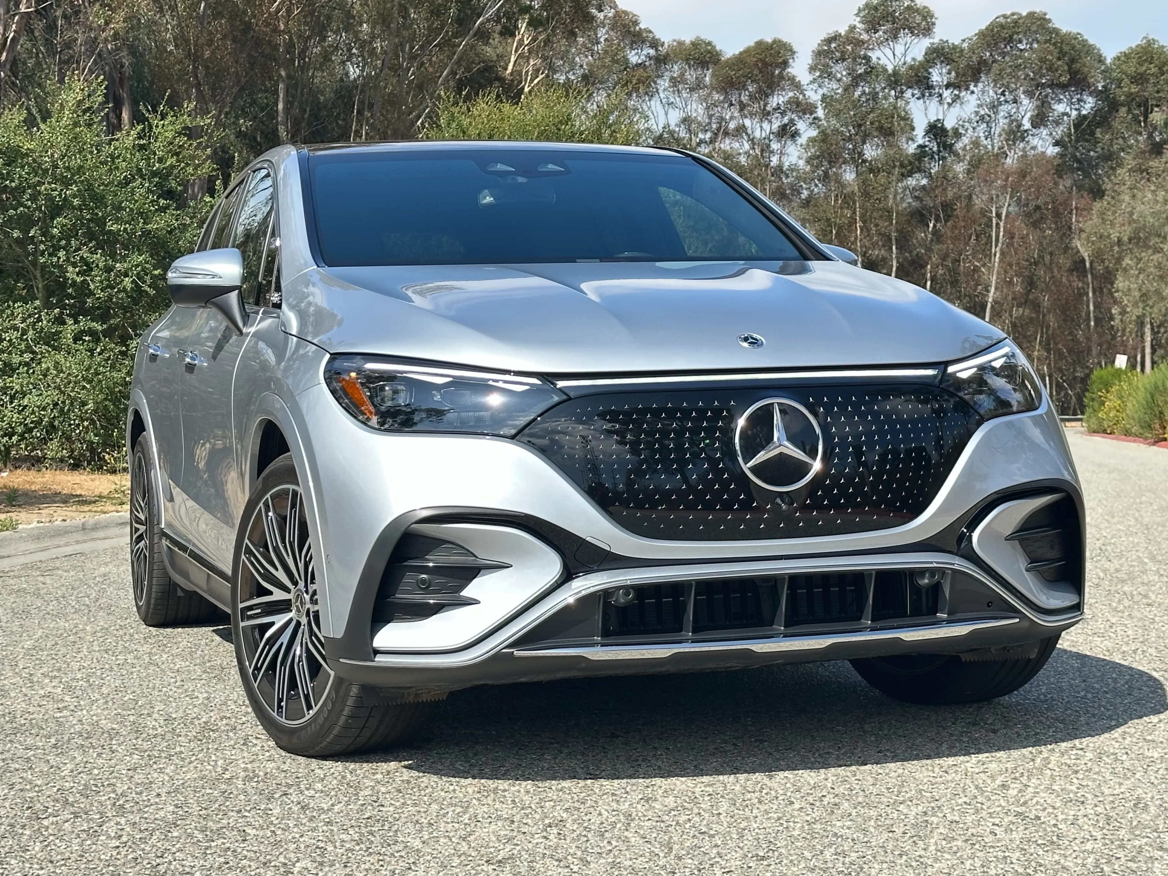 Front three-quarter view of a silver Mercedes-Benz EQE SUV parked on a road.