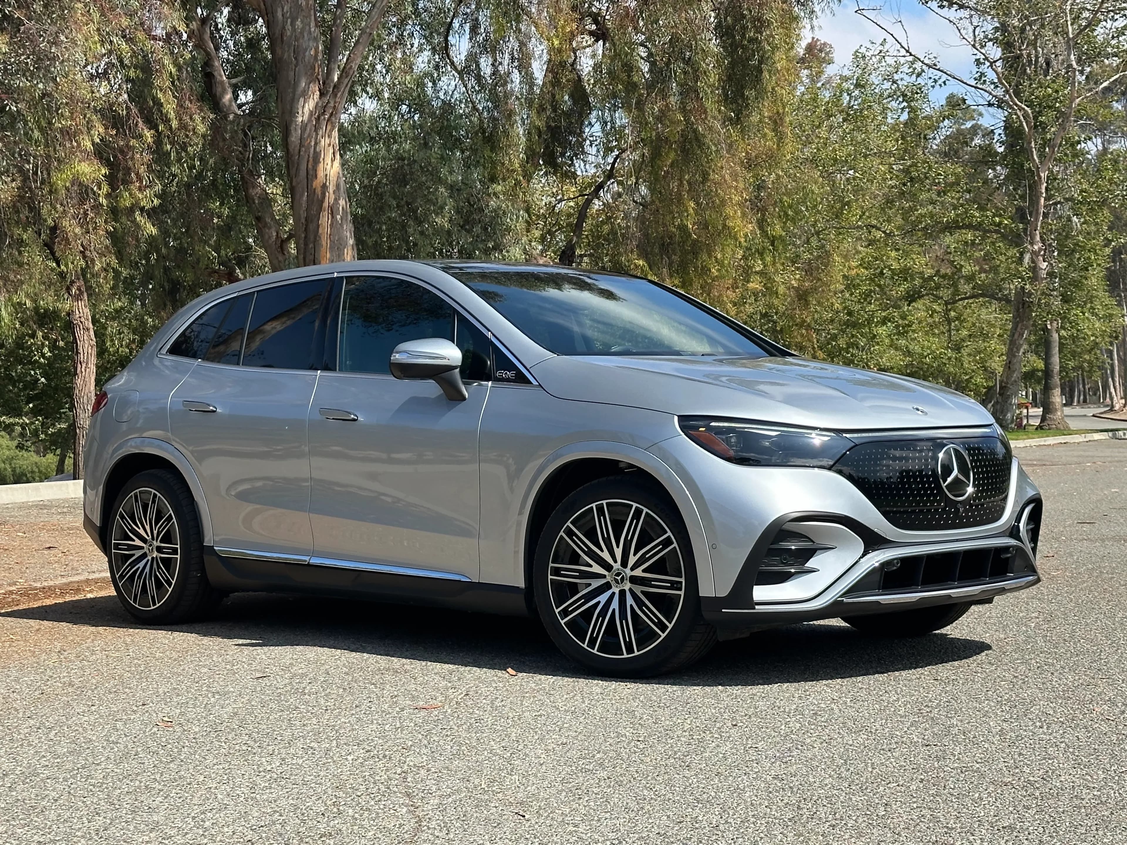Front three-quarter view of a silver Mercedes-Benz EQE SUV parked on a road.