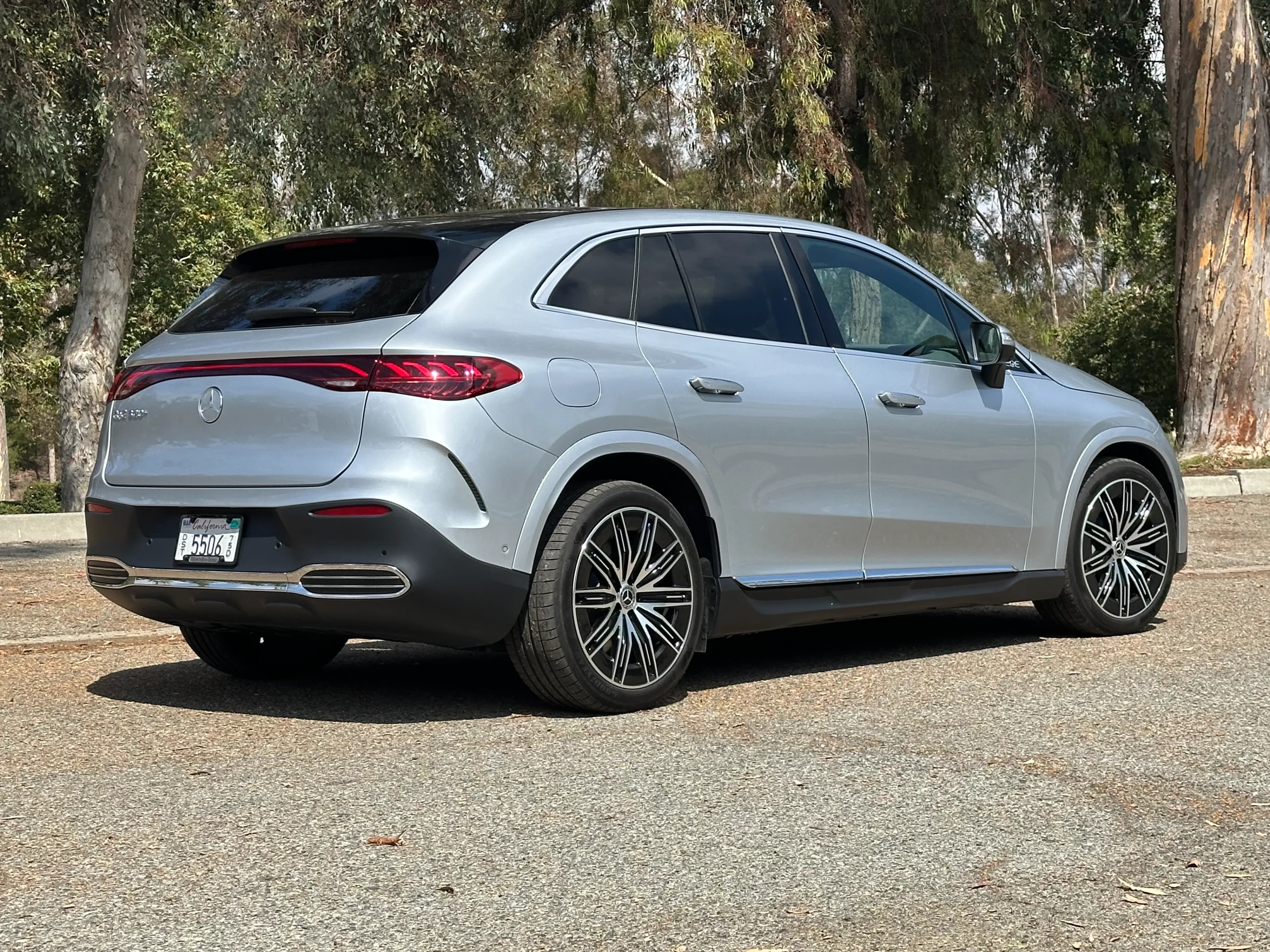 Rear three-quarter view of a silver Mercedes-Benz EQE SUV parked outdoors.