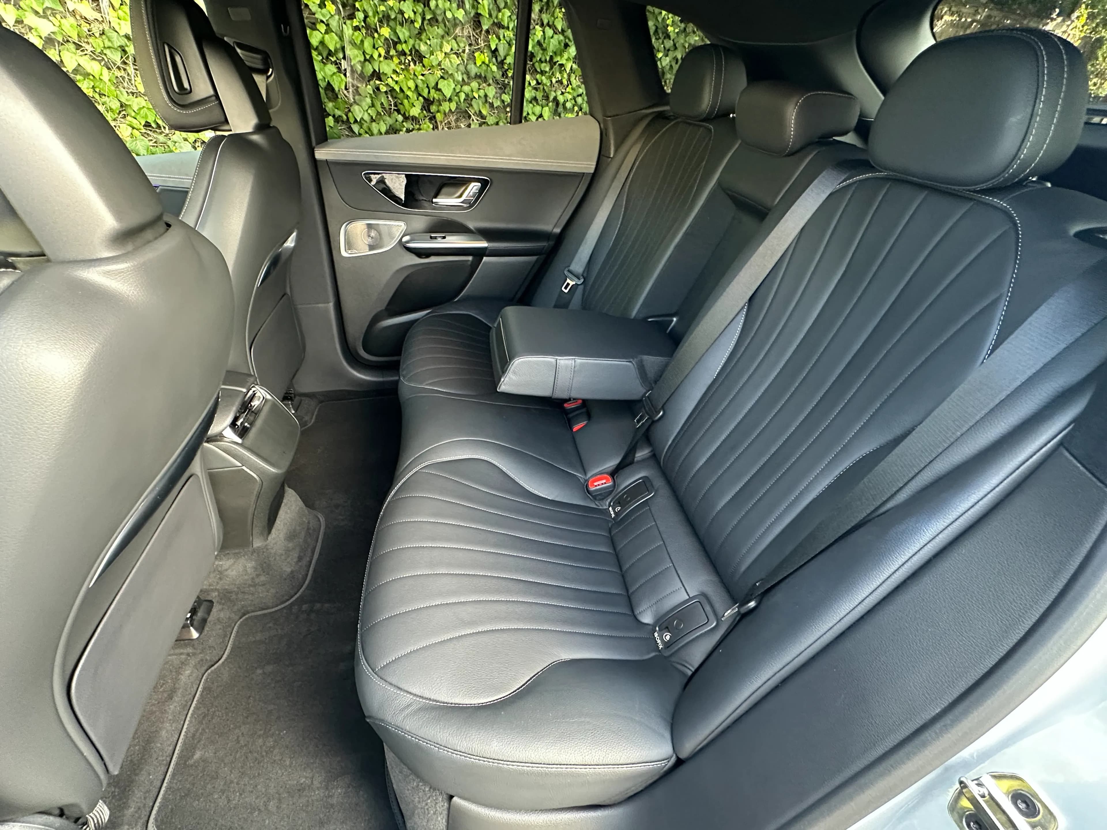 Rear seat of a Mercedes-Benz EQE SUV with black leather seats and a fold-down armrest.