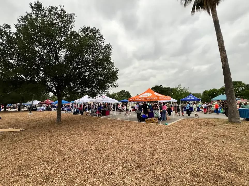 Wide view of an Earth Day event with rows of vendor tents and people walking between them.