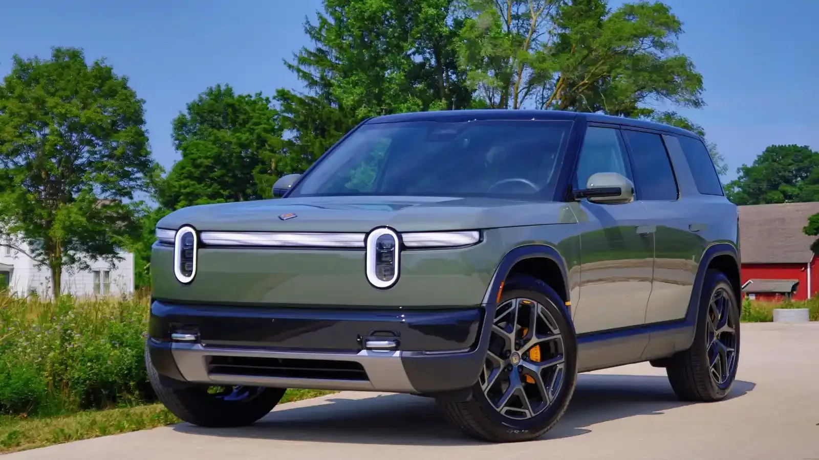 A Catalina Cove green 2027 Rivian R2 parked near a green, grassy meadow