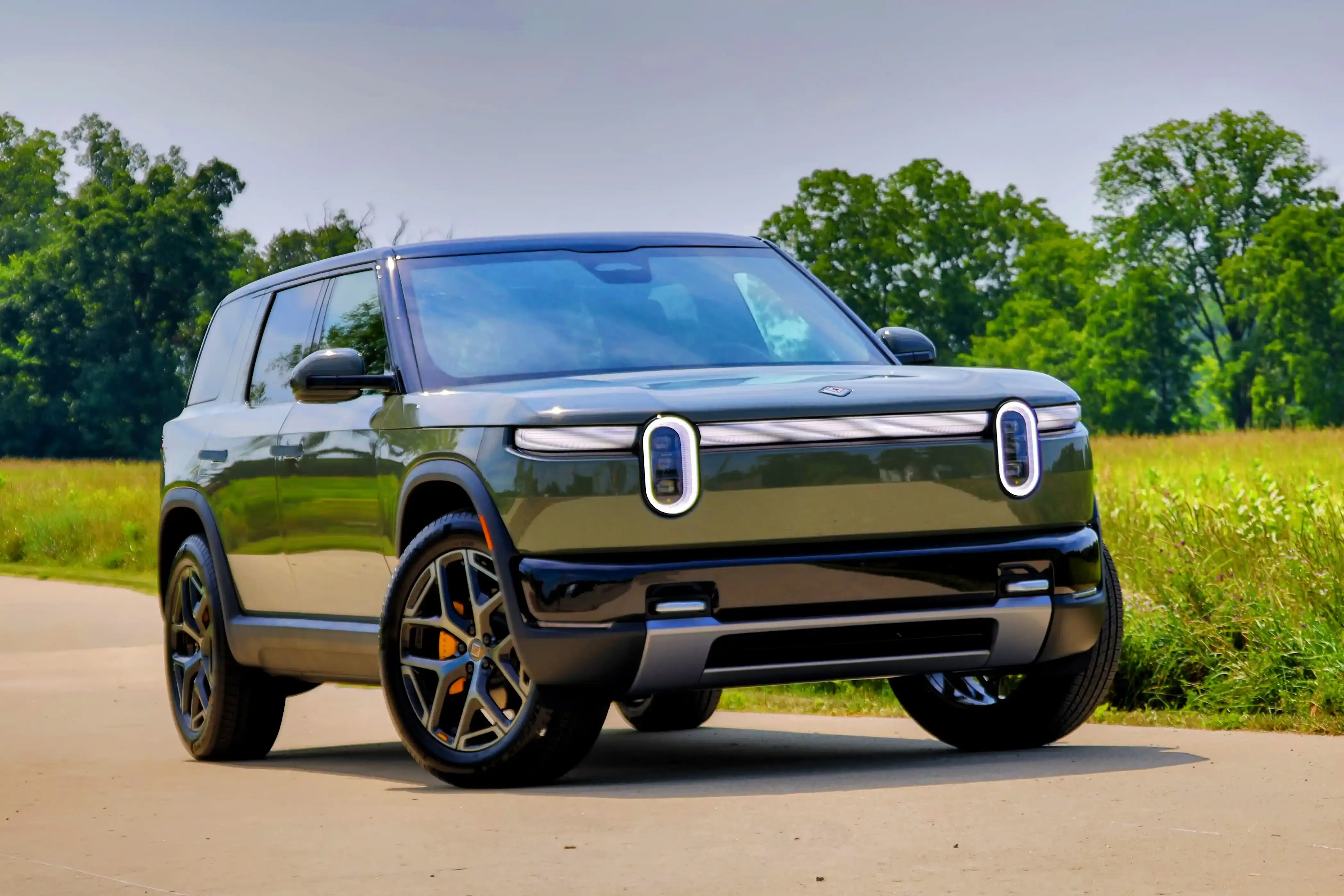 Front three-quarter view of a Rivian R2 on a country road.