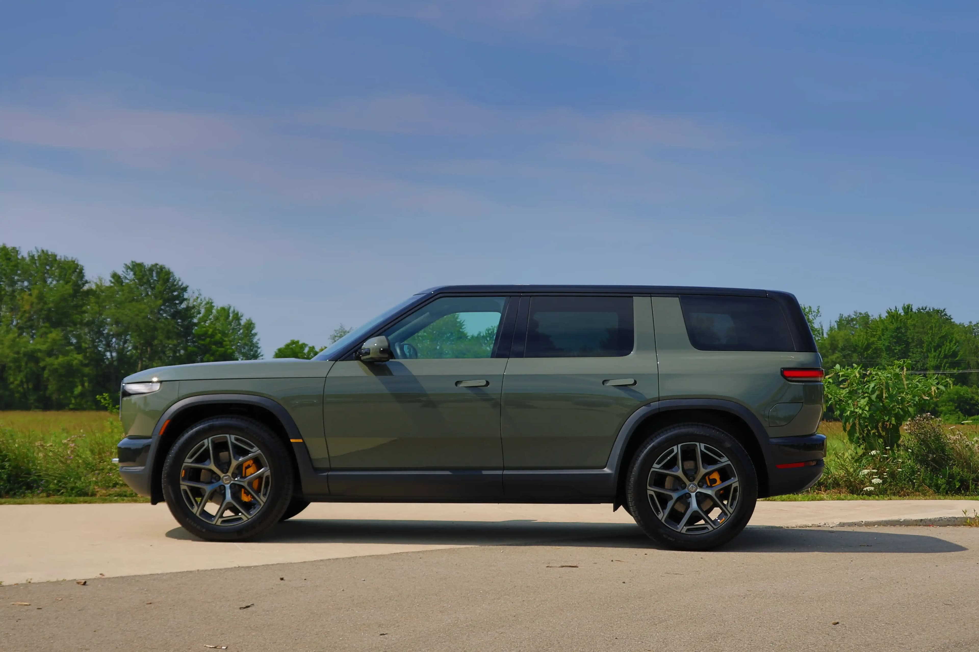 Side profile of a green Rivian R2 parked outdoors.