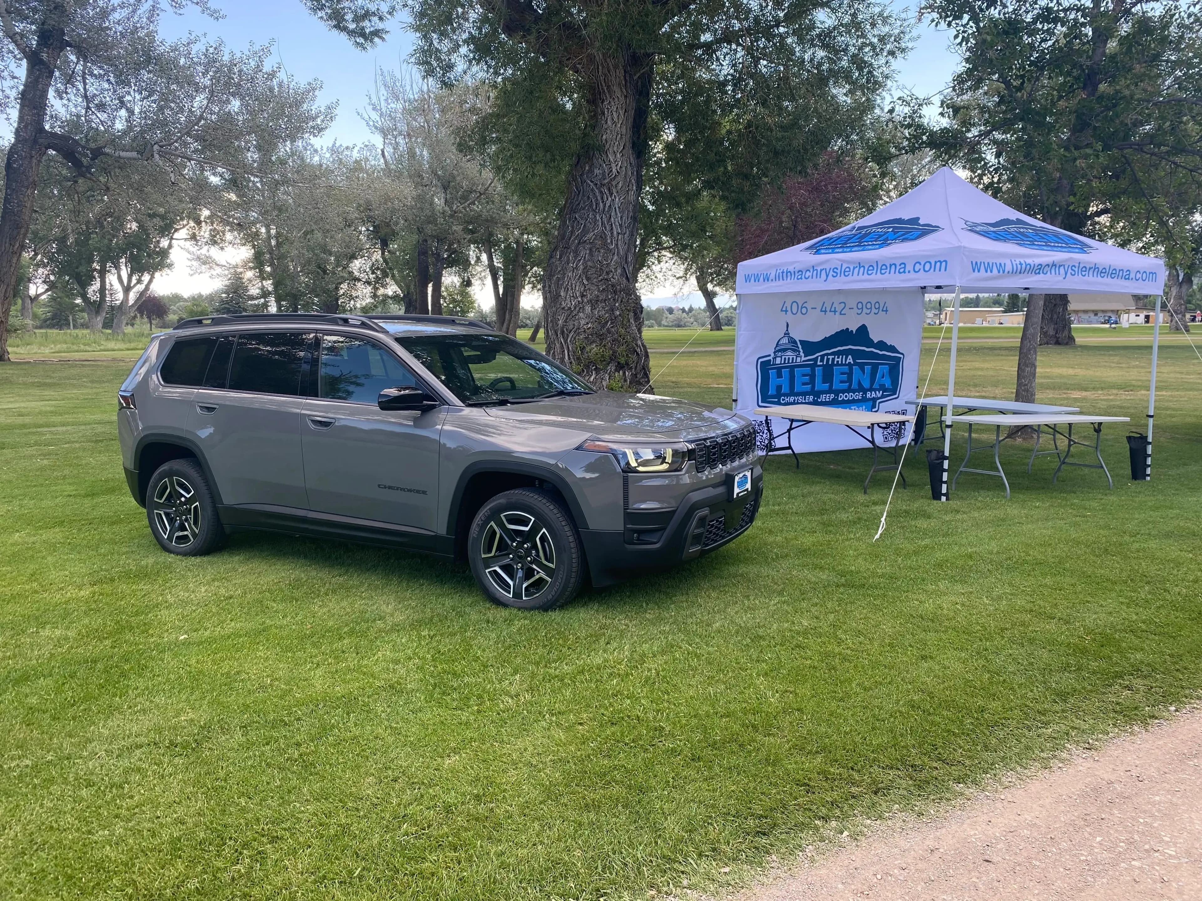 Front three-quarter view of a Jeep Cherokee parked beside a Lithia Helena tent.