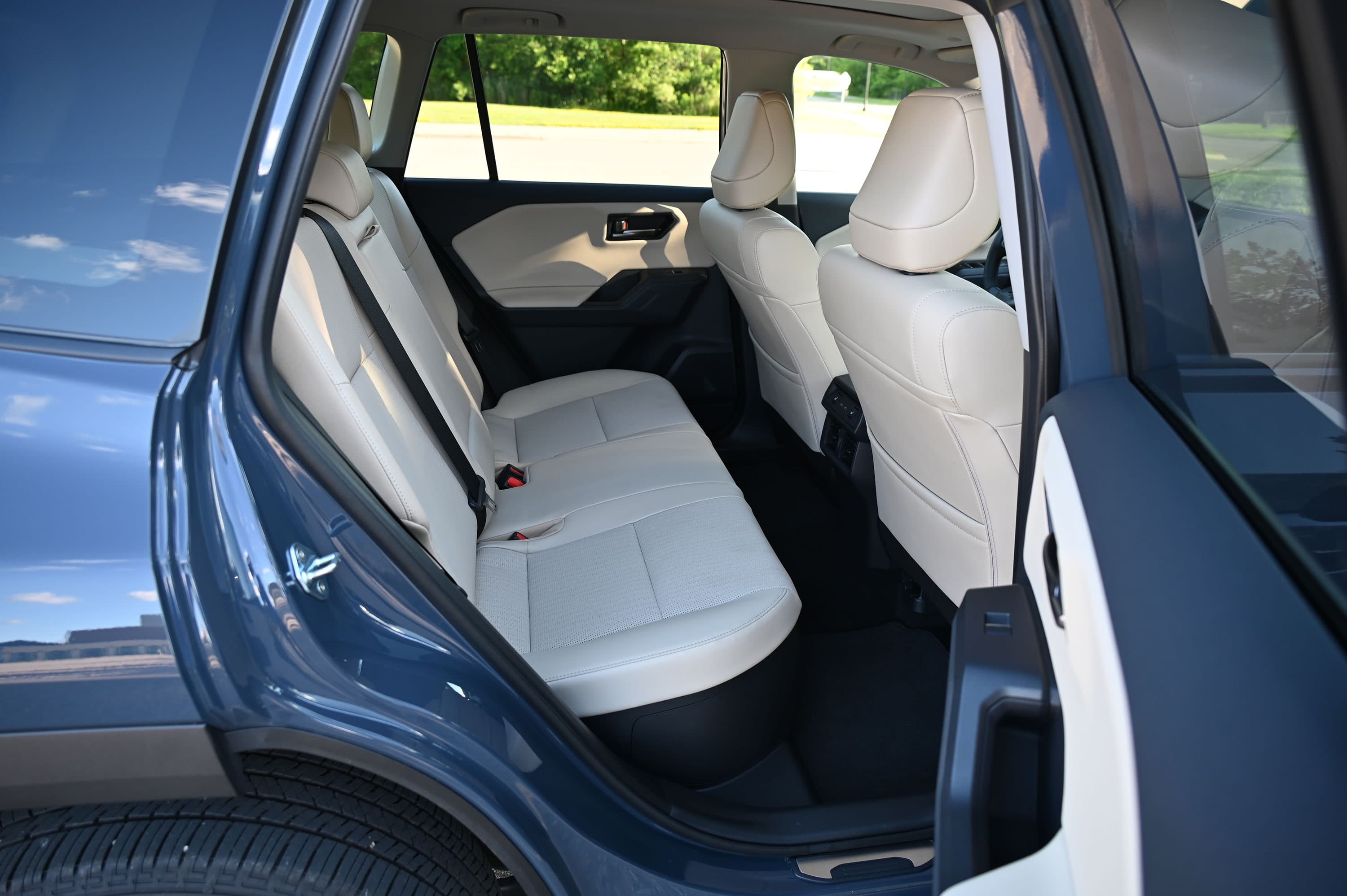 Área del asiento trasero con tapicería beige y un apoyabrazos central en una Toyota RAV4 azul.