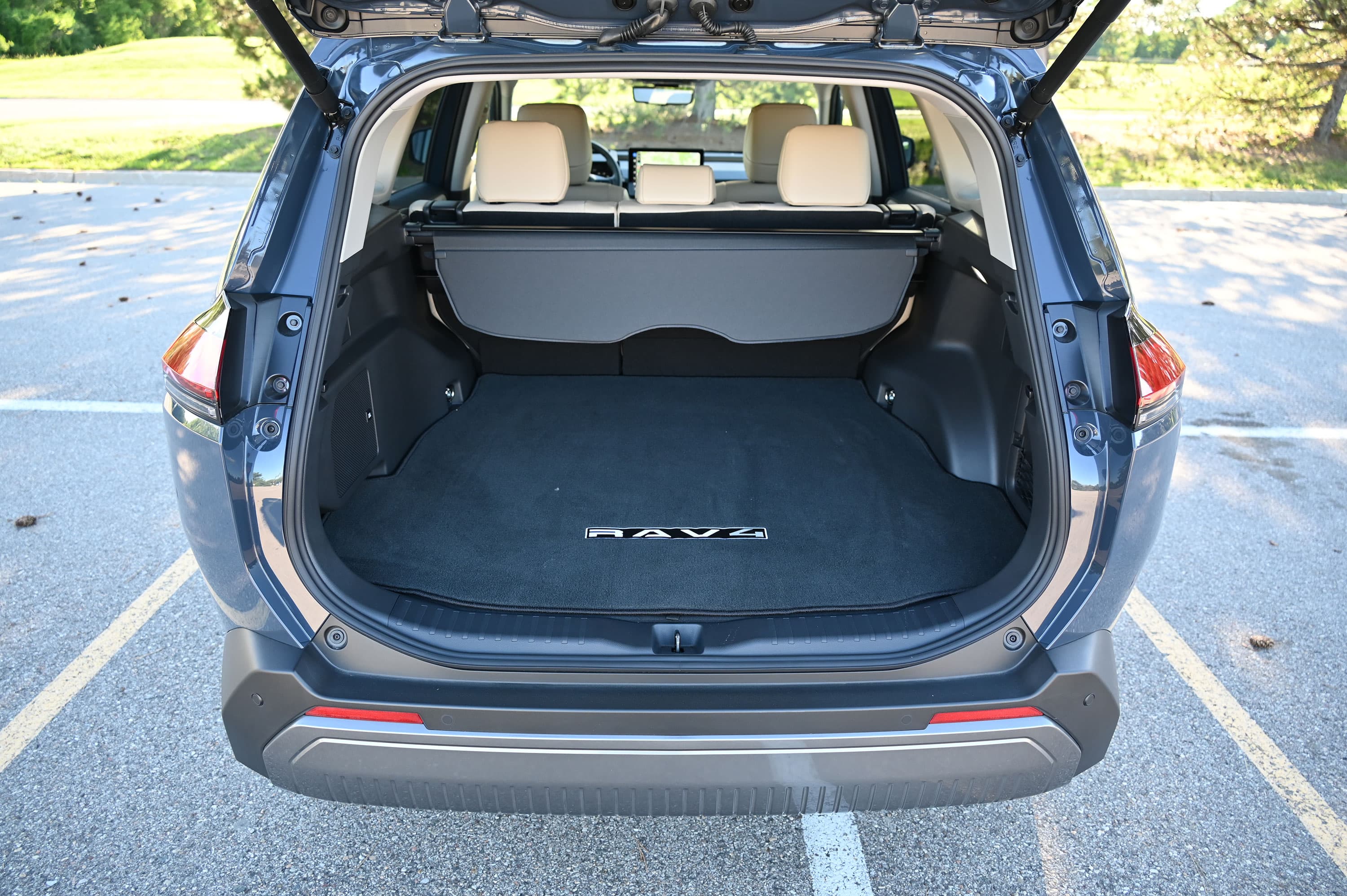 Vista trasera del área de carga de una Toyota RAV4 con la compuerta abierta y los asientos traseros levantados.